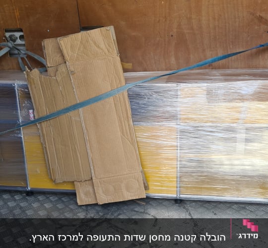 ארגזים וקרטונים קשורים ברצועות בתוך משאית